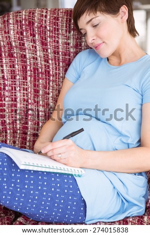 Pregnant woman listing baby names at home in the living room