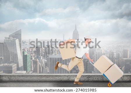 Delivery man with trolley of boxes running against cityscape