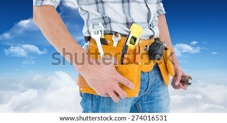 Cropped image of technician with tool belt around waist against bright blue sky with clouds