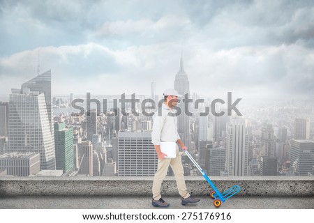Delivery man pushing empty trolley on white background against cityscape