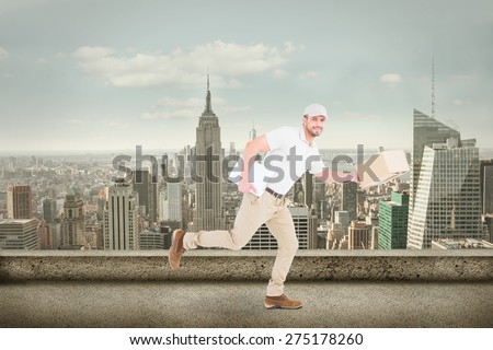 Delivery man with cardboard boxes running against cityscape