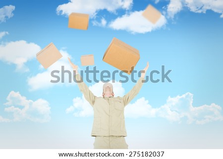 Excited delivery man with arms raised looking up against blue sky