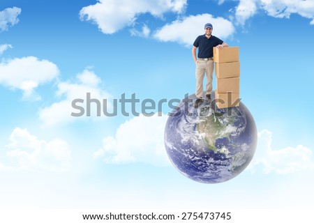 Happy delivery man with cardboard boxes against blue sky