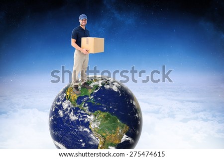 Happy delivery man holding cardboard box against white clouds under blue sky