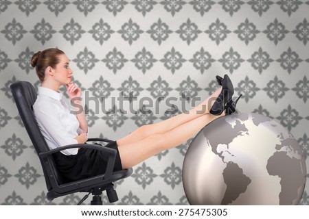 Businesswoman sitting on swivel chair with feet up against grey wallpaper