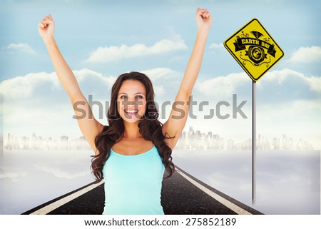 Casual brunette cheering at camera against road leading to city
