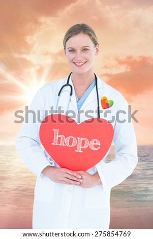 The word hope and doctor holding red heart card against sunrise over magical sea