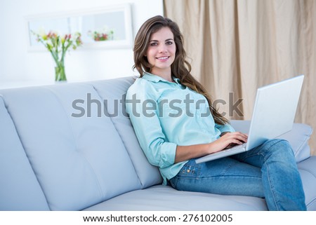Happy woman using her laptop on couch at home in the living room