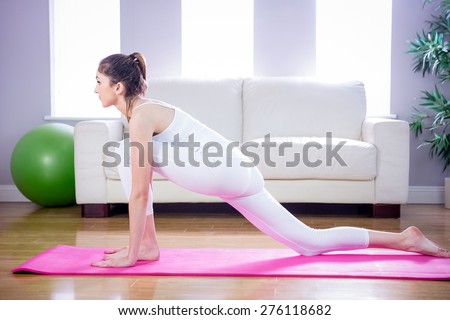 Fit woman doing yoga on mat at home in the living room