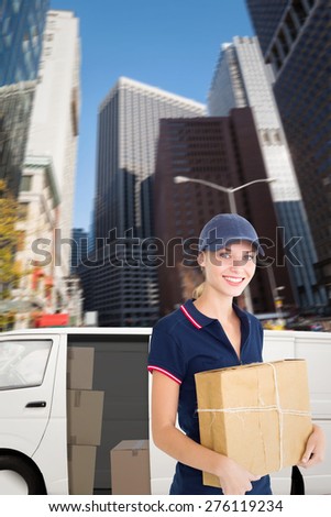 Happy delivery woman holding cardboard box against new york