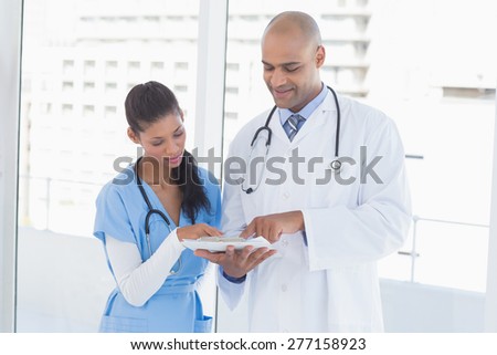 Smiling doctors reading files in medical office