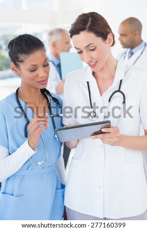 Beautiful female doctors working together with tablet in medical office