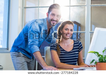 Smiling colleagues working together on computer in the office