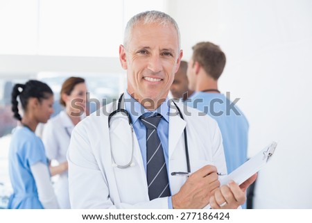 Confident male doctor smiling at camera in medical office