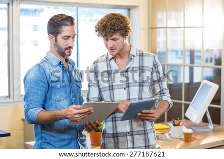 Business team looking at clipboard and tablet in the office