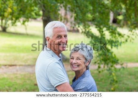 Happy old couple smiling in a park on a sunny day
