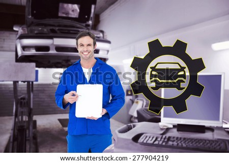 Confident mechanic showing blank clipboard against auto repair shop