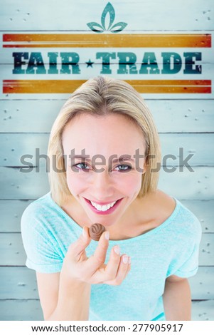 Smiling blonde holding box of chocolates against wooden planks