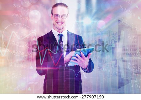 Happy businessman using his tablet pc against room with large window looking on city