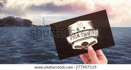 Hand showing card against calm sea with lighthouse