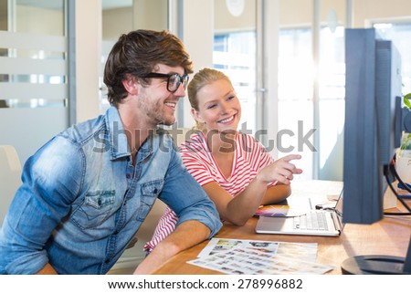 Smiling business team working together with computer in the office