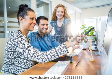 Smiling business team working together with computer in the office