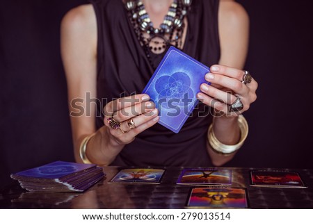 Fortune teller forecasting the future with tarot cards on black background