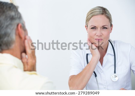 Doctor examining patient with neck ache in medical office
