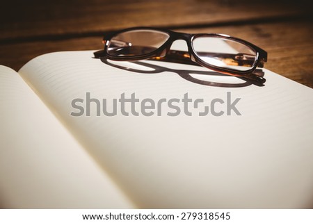 Empty notepad with reading glasses on a desk