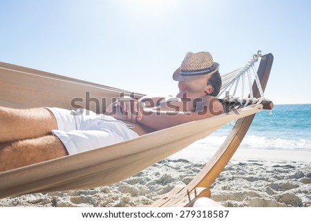 Handsome man resting in the hammock at the beach