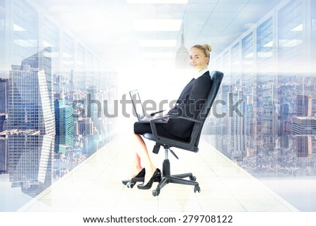 Businesswoman sitting on swivel chair with laptop against digitally generated server room with towers