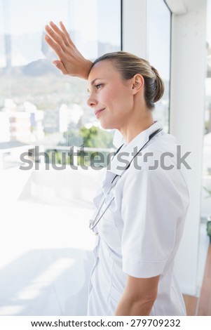Confident female doctor looking through windows in hospital