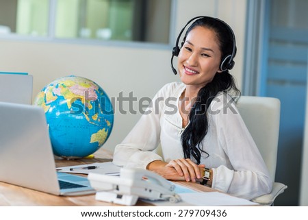 Pretty travel agent smiling at camera in the office