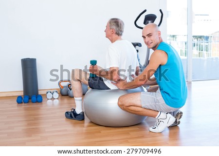 old man having back massage on exercise ball in medical office