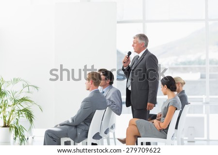 Businessman talking in microphone during conference in meeting room