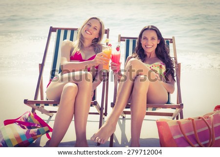 Cute friends having cocktails on the beach on a sunny day