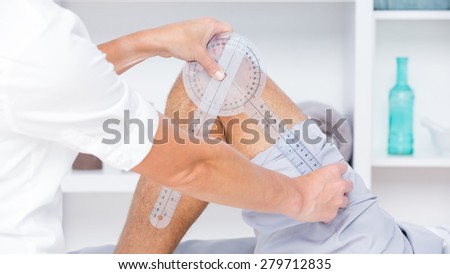 Doctor examining man leg with tool in medical office