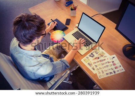 Happy designer working on his laptop in creative office