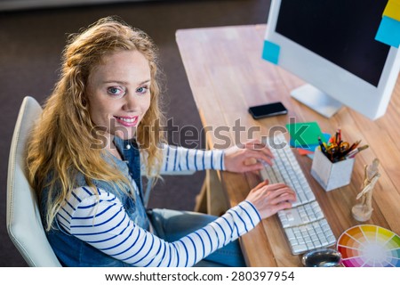 Smiling designer typing on keyboard in the office