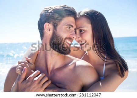 Happy couple hugging and smiling at each other at the beach