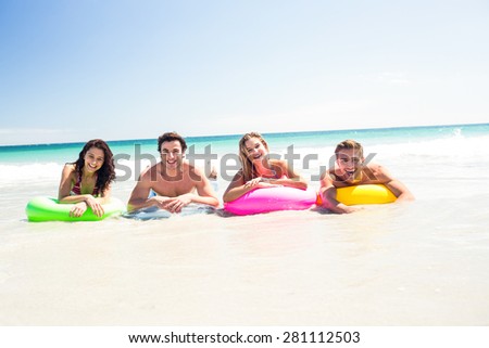 Happy friends lying on inflatable mattress above the water at the beach