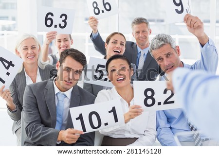 Smiling interview panel holding score cards in bright office
