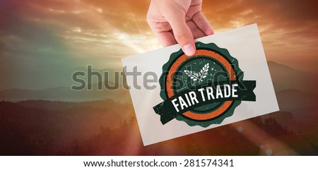 Hand showing card against sunrise over mountains