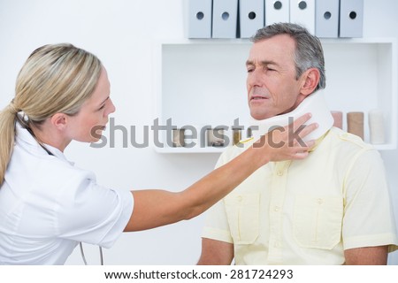 Doctor examining patient wearing neck brace in medical office