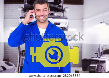 Portrait of smiling male mechanic using mobile phone against auto repair shop