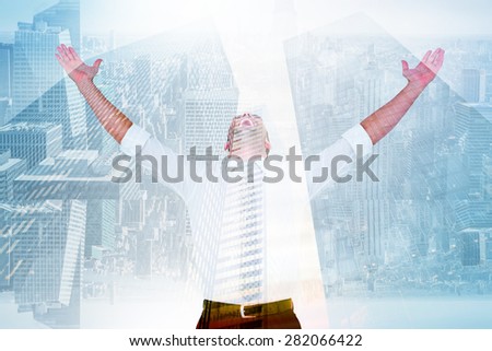 Handsome businessman cheering with arms up against low angle view of skyscrapers