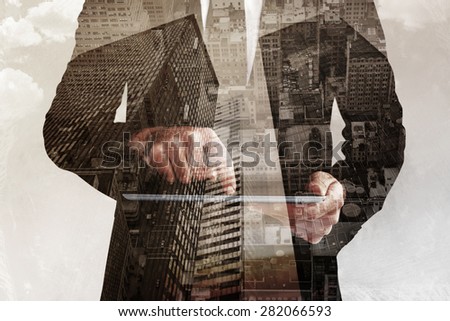Businessman using his tablet pc against low angle view of skyscrapers