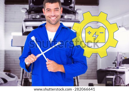 Smiling male mechanic holding lug wrench against auto repair shop