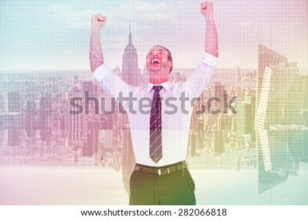 Handsome businessman cheering with arms up against server room with towers