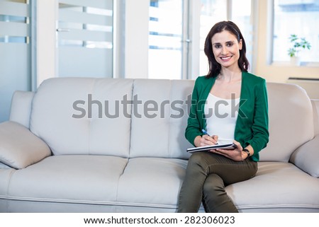 Psychologist sitting on the couch and taking notes in the office